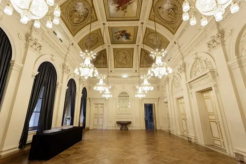 Salle de bal avec plafond peint, lustres en cristal et hautes fenêtres cintrées