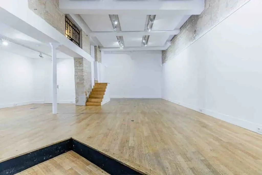 Salle avec parquet, escalier et mur de grandes fenêtres