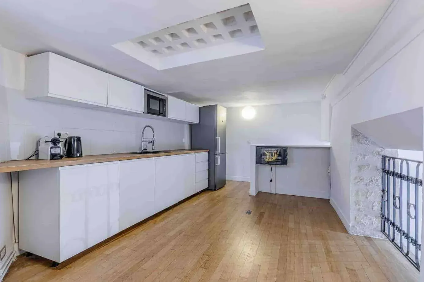 Cuisine aux meubles blancs et mur de pierre