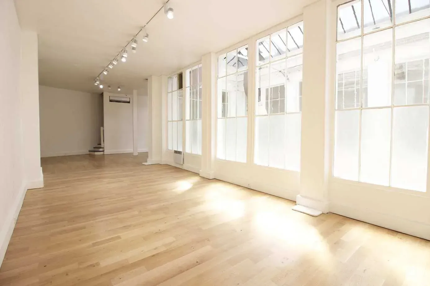 Hall lumineux aux grandes baies et parquet clair