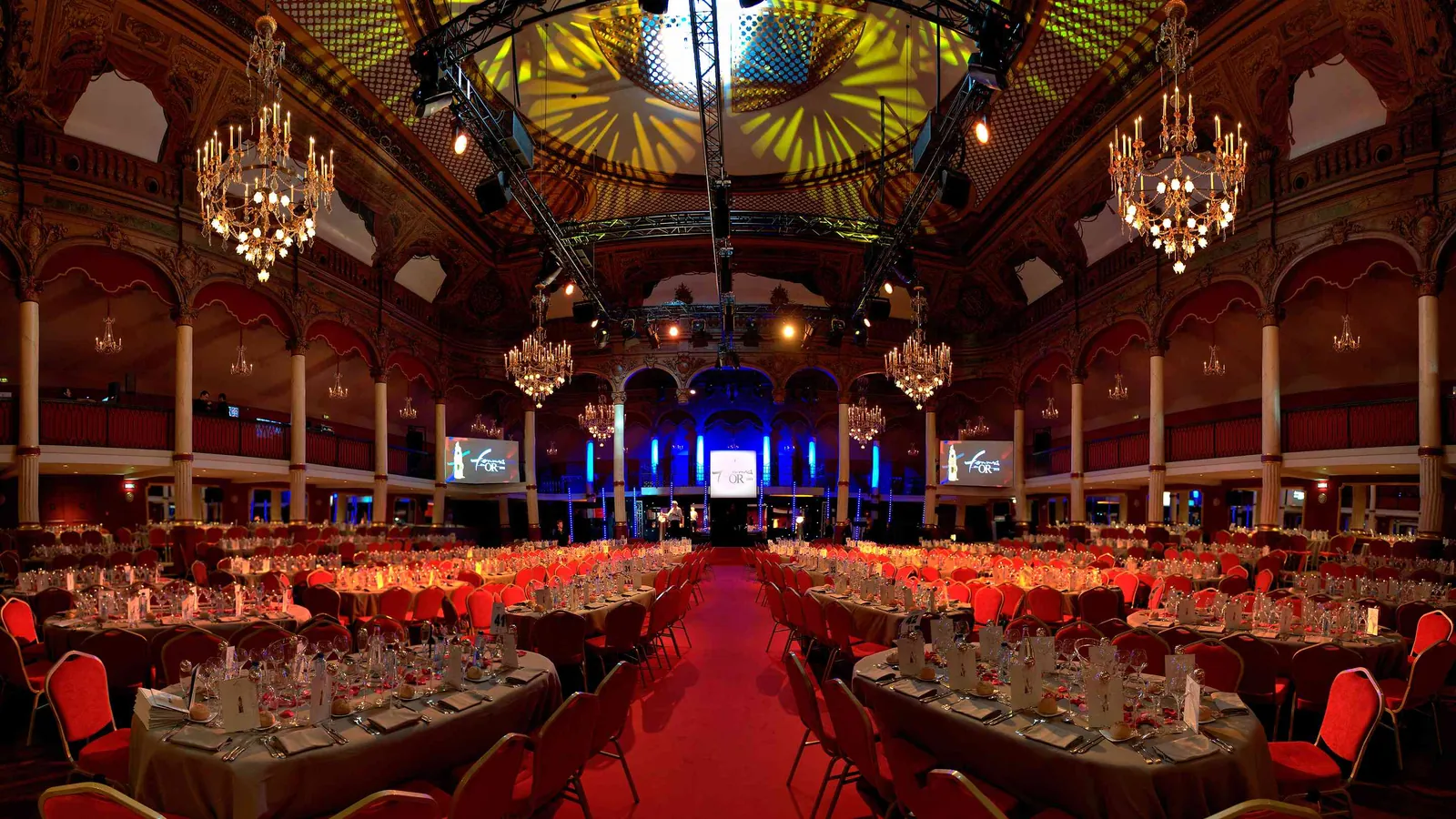 Dîner de gala au Grand Hall Étoile sous les lustres, tables de banquet et chaises rouges