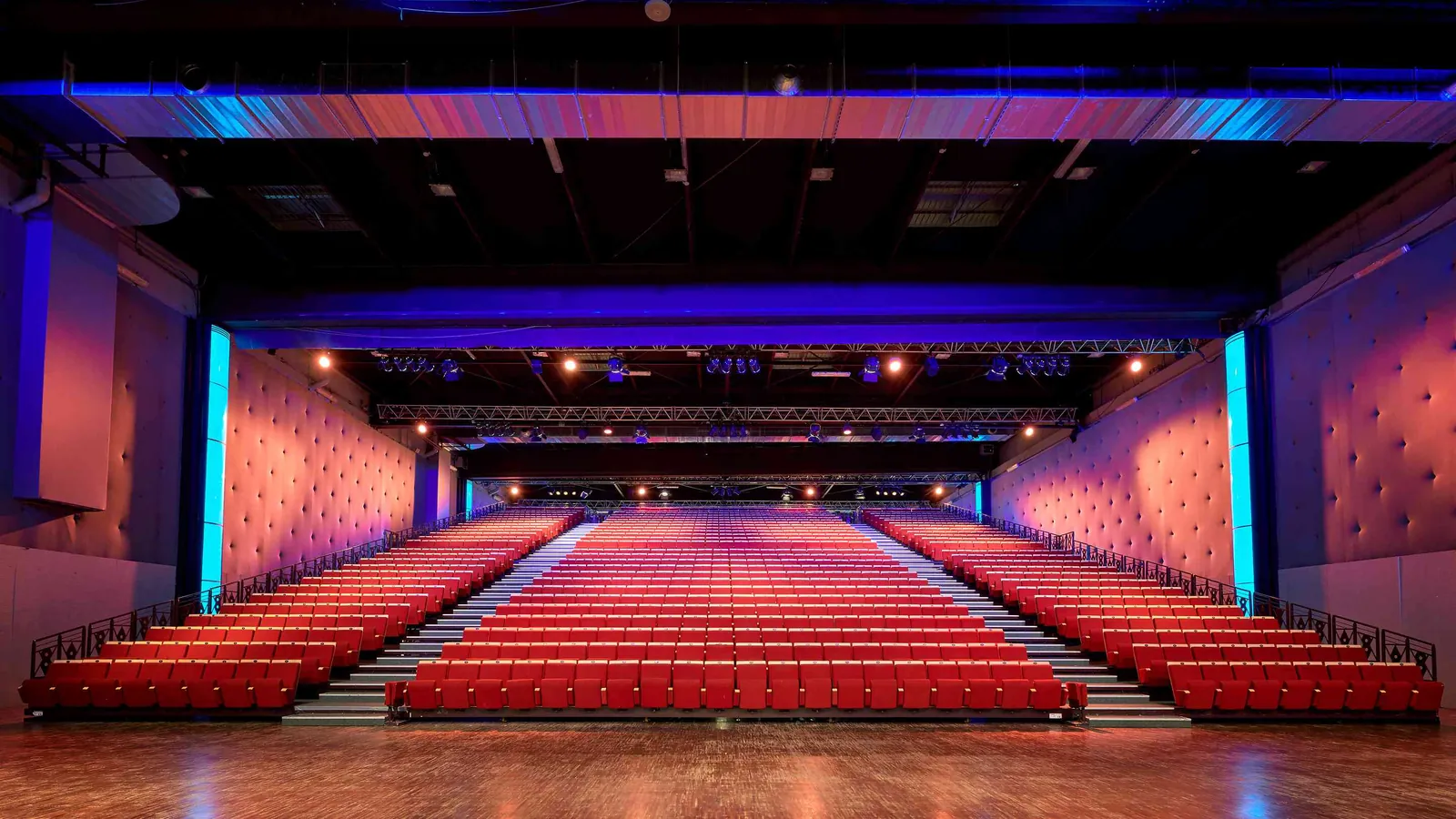 Grande salle des Grandes Halles Seine en configuration théâtre, sièges rouges et éclairage bleu