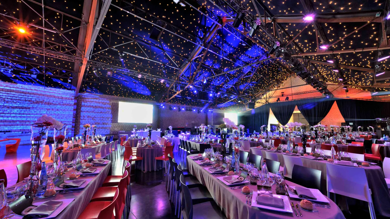 Dîner de gala aux Grandes Halles Seine avec tables de banquet, couverts et plafond étoilé