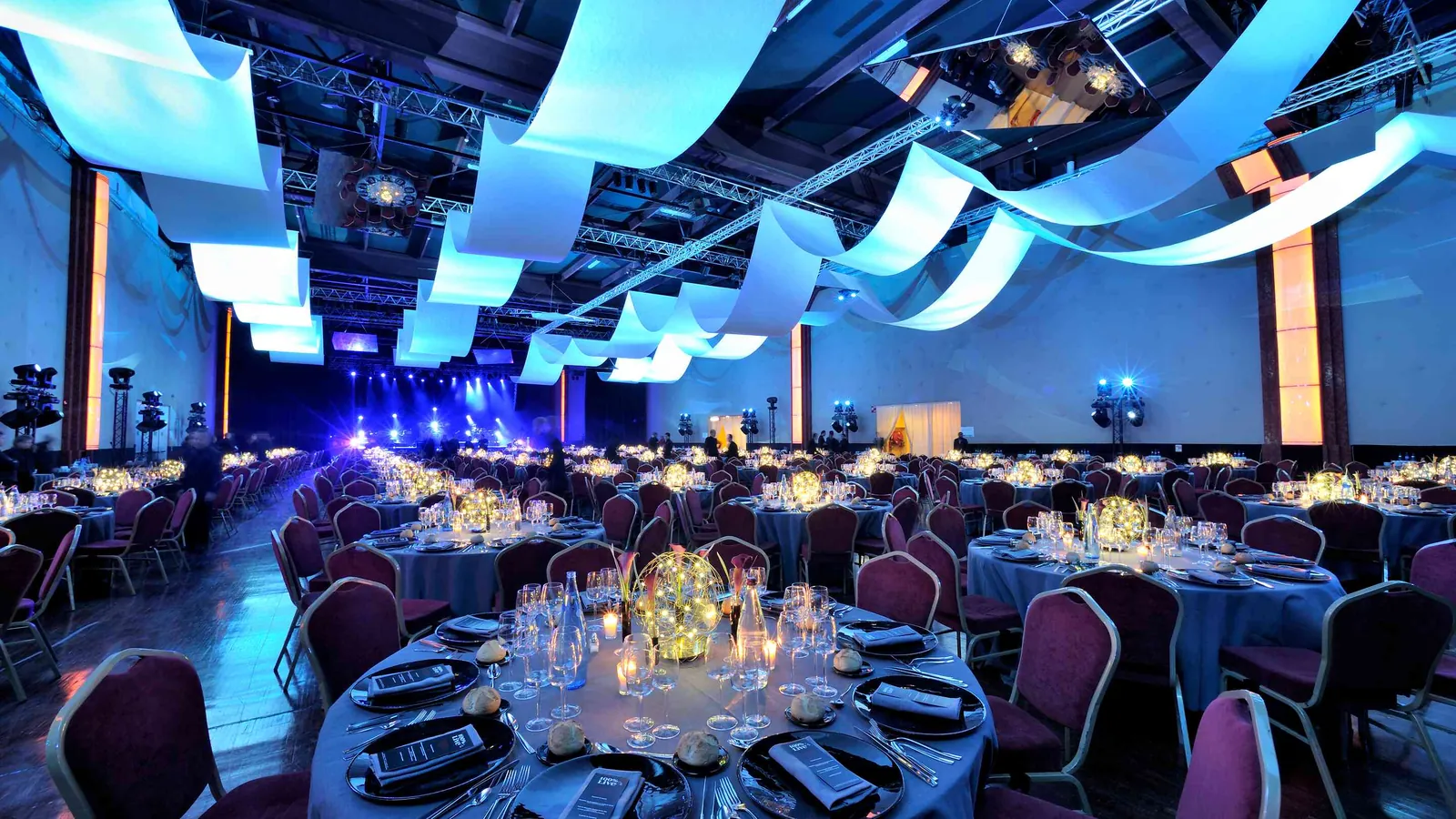Salle de banquet des Grandes Halles Seine avec tables rondes et rubans lumineux suspendus