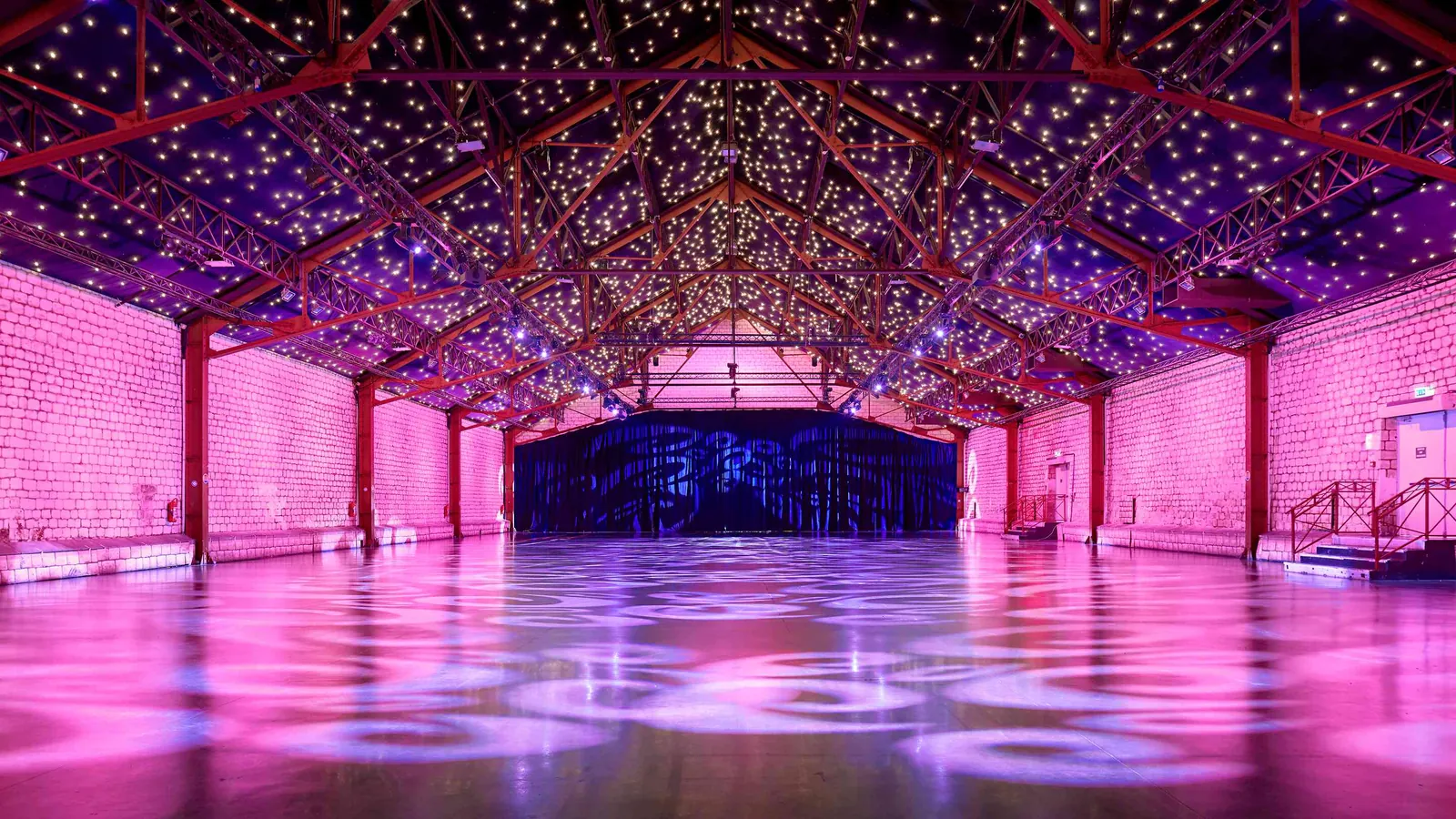 Grande halle des Grandes Halles Seine, plafond étoilé, charpente apparente et lumière rose