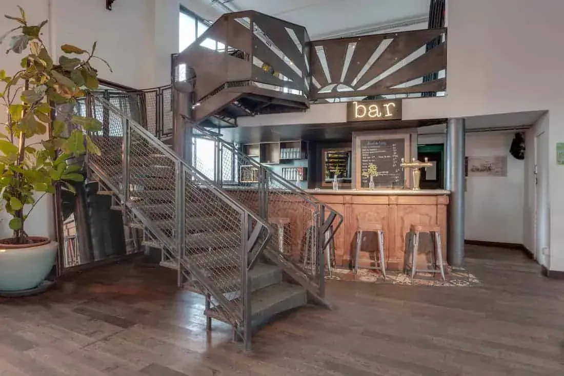 Bar counter beneath a metal staircase leading to the mezzanine
