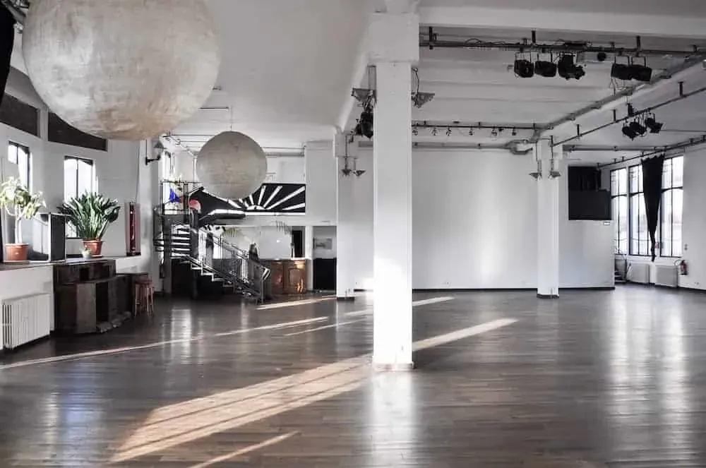 Large industrial hall with white columns, paper lantern lights and a wooden floor