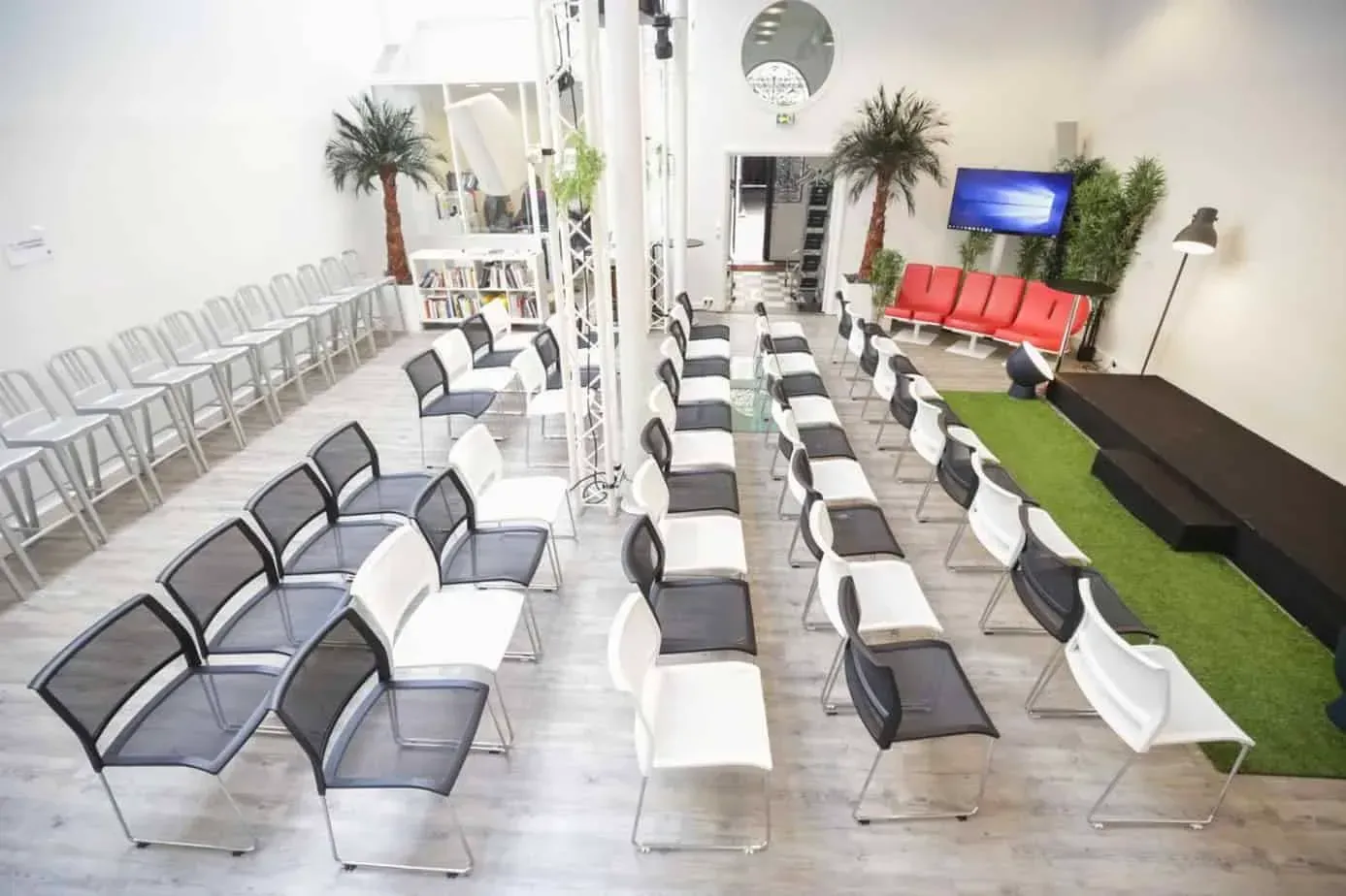 Room with a stage area, palm plants and a strip of green carpet