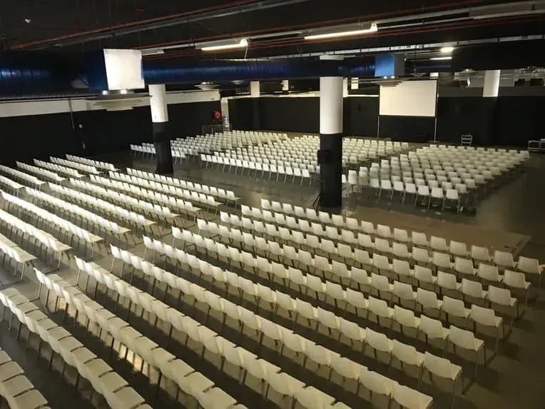 Large industrial hall with rows of chairs facing a stage