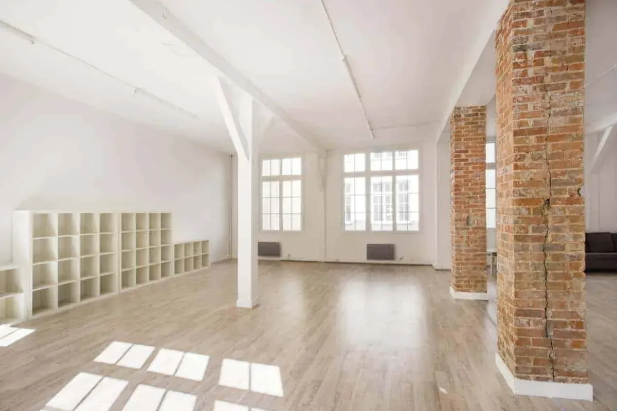 Loft with white shelving units and sunlight across the wooden floor