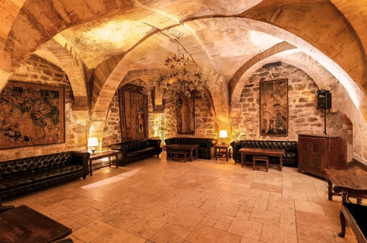 Vaulted cellar lit by warm lamps and tapestries