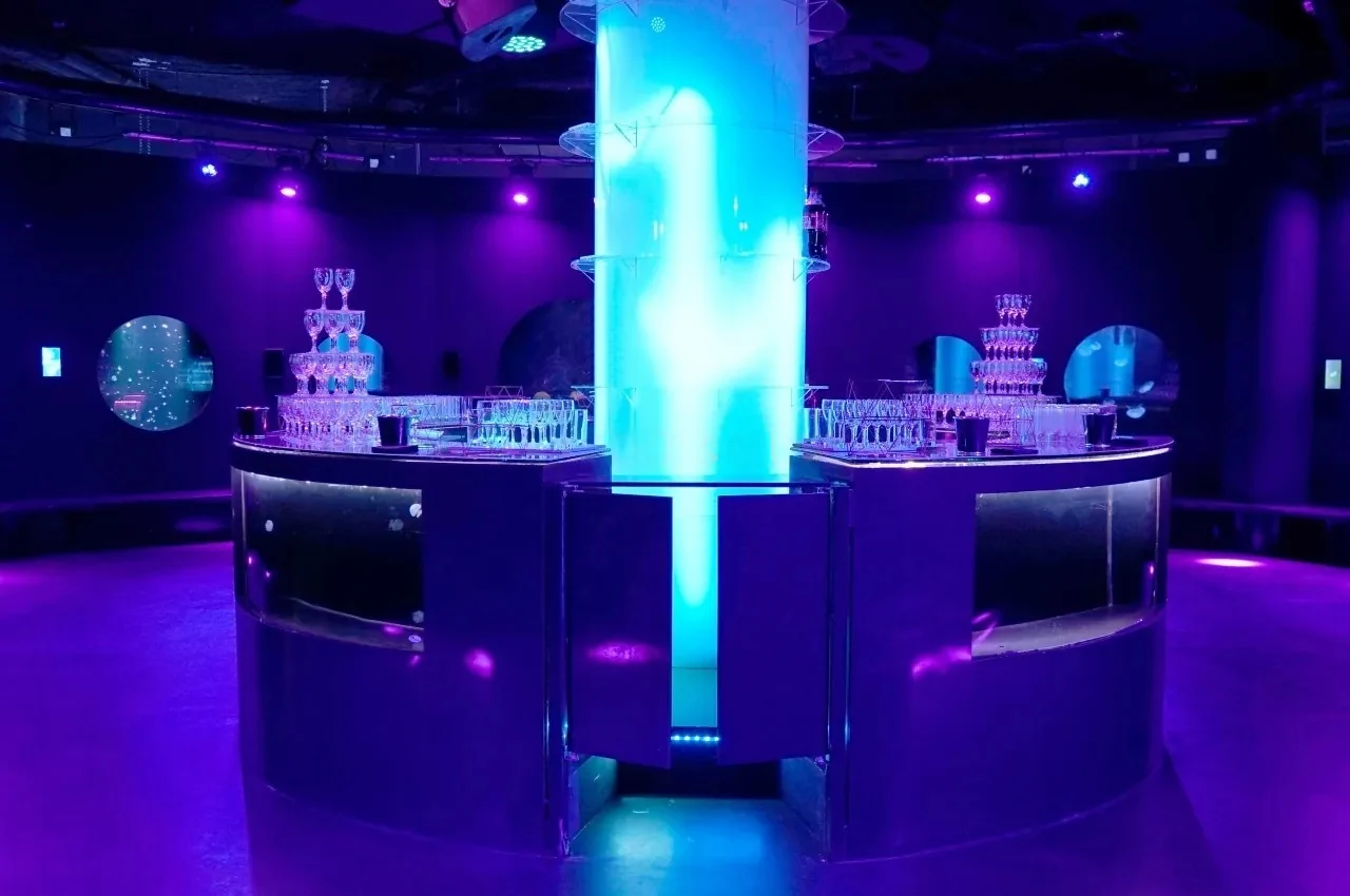 Central bar in a blue-lit room with a tall lit column