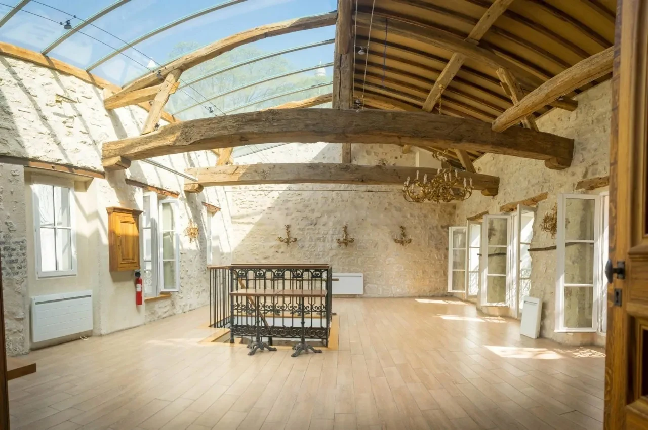 Room with stone walls, beams and light from tall windows