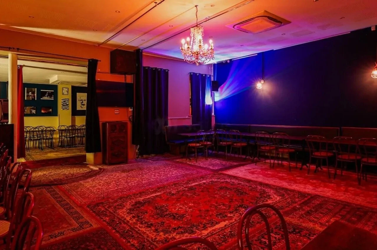 Room with a chandelier, stage lights and a red rug