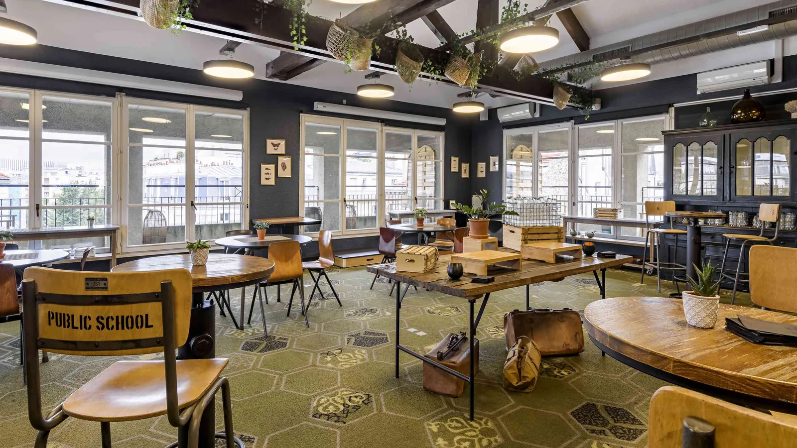 Salle café de la Maison des Ateliers avec chaises d'école vintage, moquette et longue banque