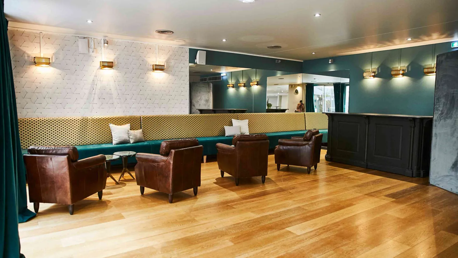 Golden House bar lounge with a teal banquette, leather armchairs and wall sconces