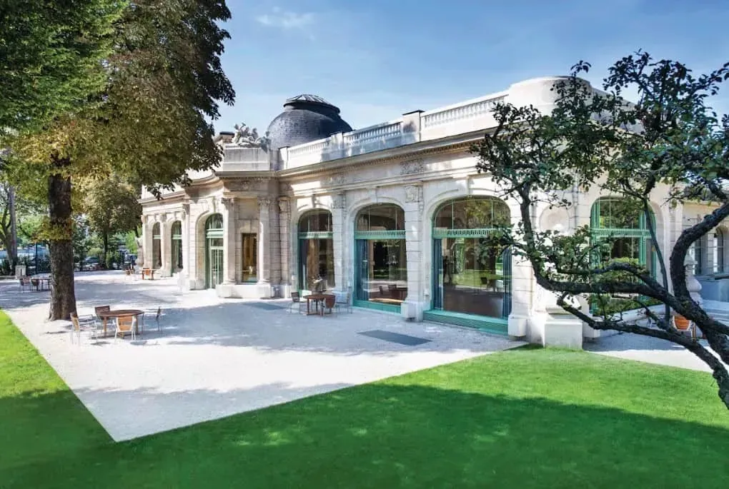 Neoclassical pavilion facade with tall windows and a lawn in front