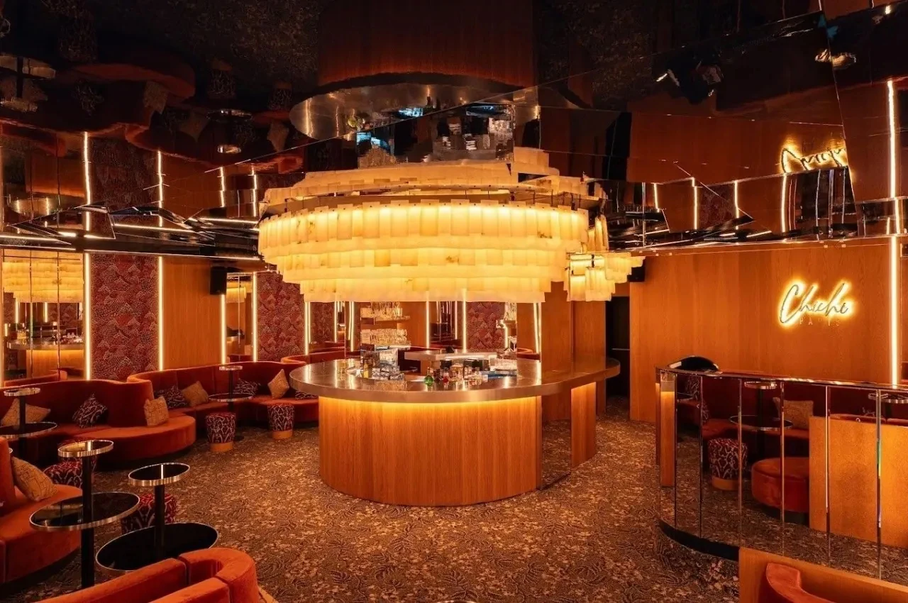 Round central bar under a backlit illuminated ceiling in a warm, mirrored room.