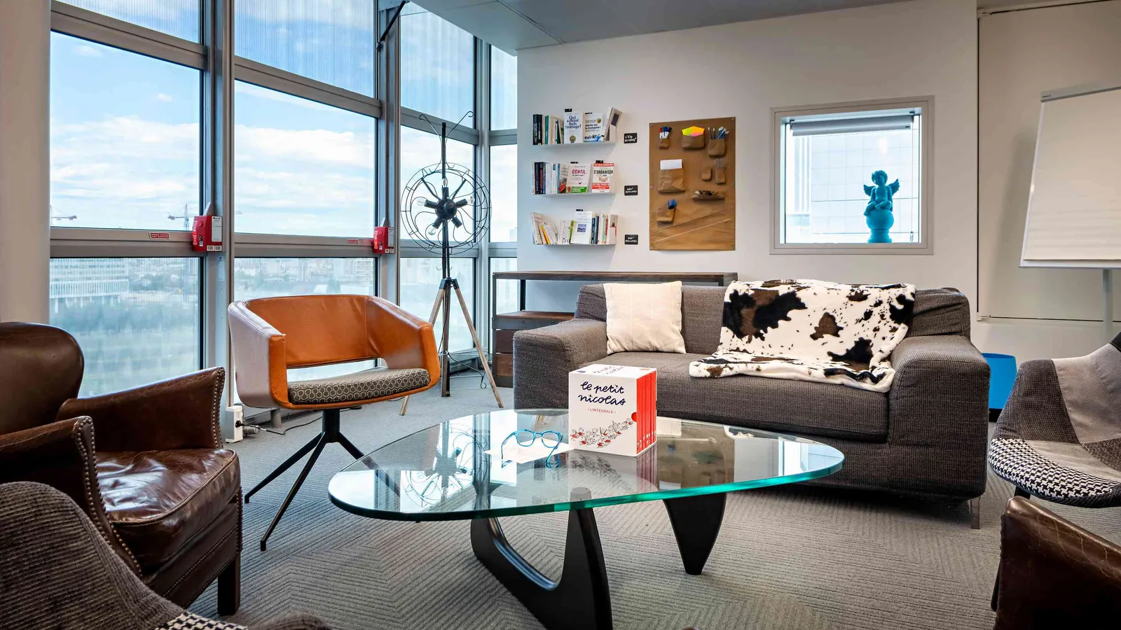 Salon du Pavillon Ouest avec fauteuil en cuir, table basse en verre et vue sur la ville