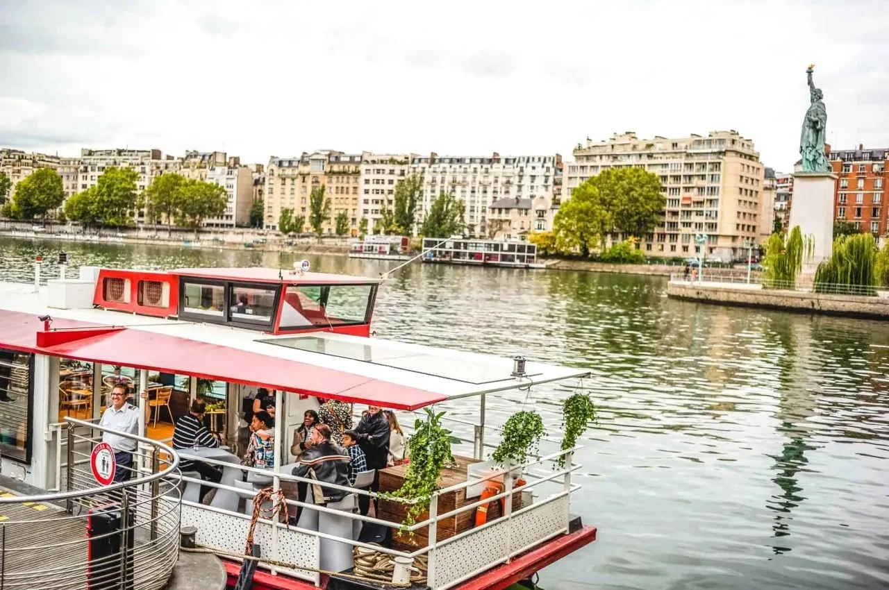 Red and white river boat on the Seine near the Statue of Liberty