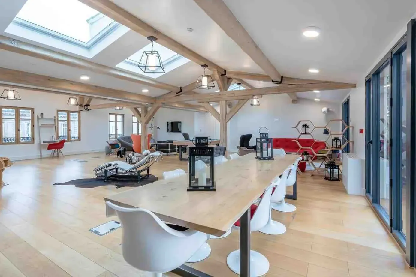 Salon de penthouse aux poutres apparentes, verrières et longue table en bois avec chaises blanches
