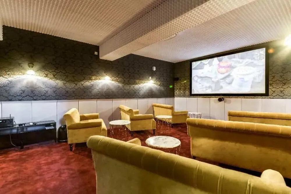 Room with yellow sofas facing a wall-mounted screen