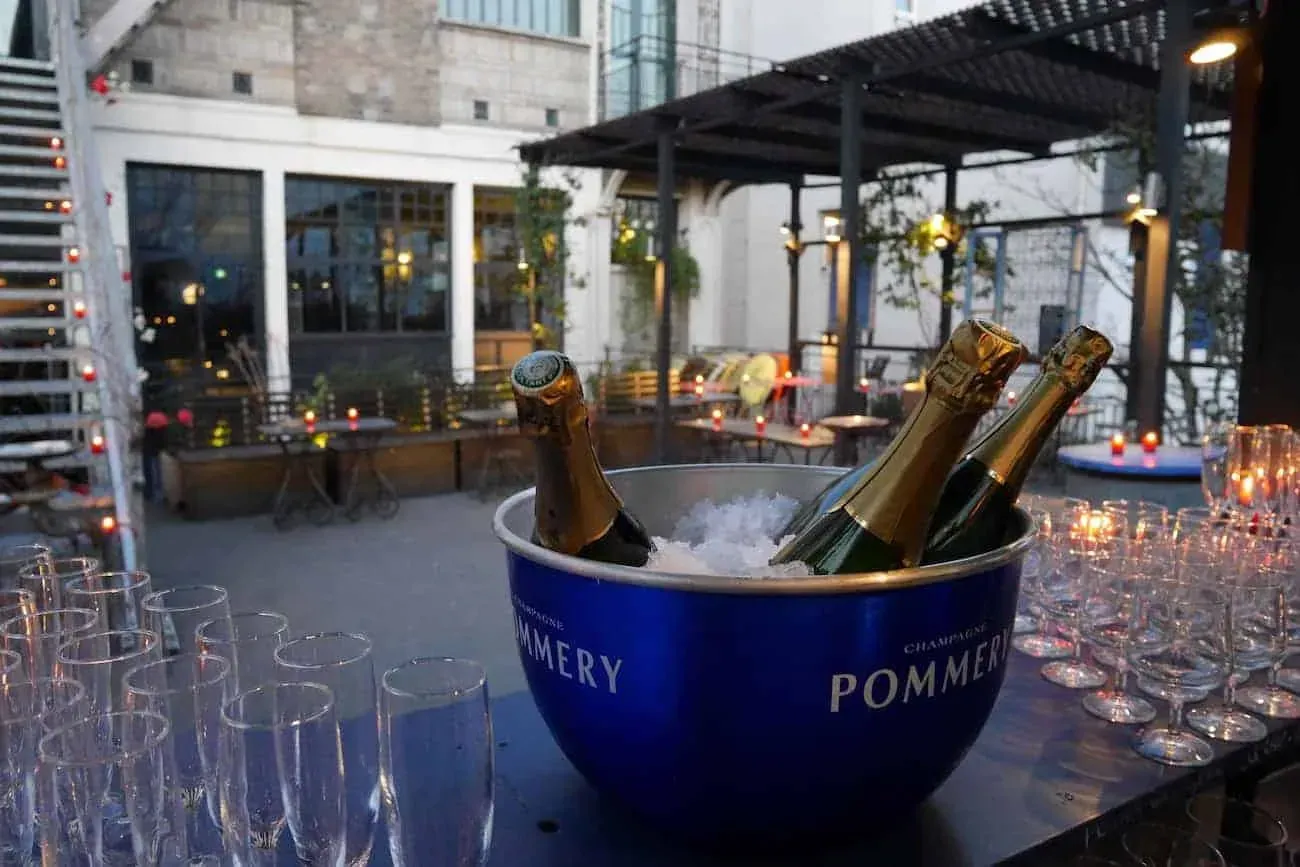 Seau à champagne et verres dressés sur une terrasse sous pergola