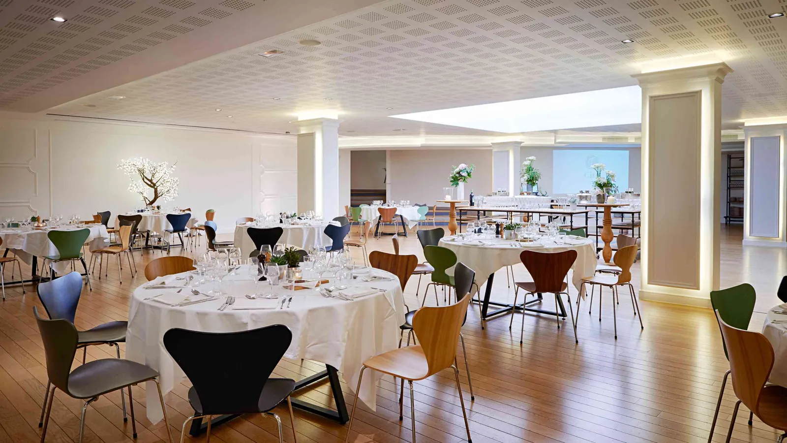 Salle de banquet des Salons des Moulures avec tables rondes nappées près des fenêtres