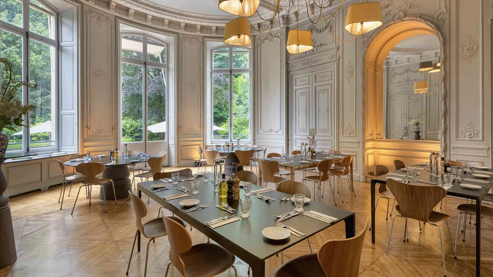 Salle à manger des Salons des Moulures avec parquet, lustres et tables dressées pour un dîner