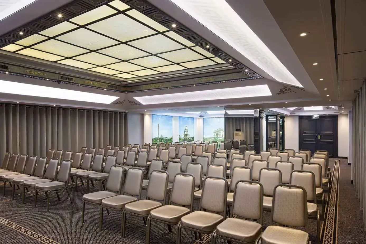 Rows of chairs under a decorated ceiling facing a screen