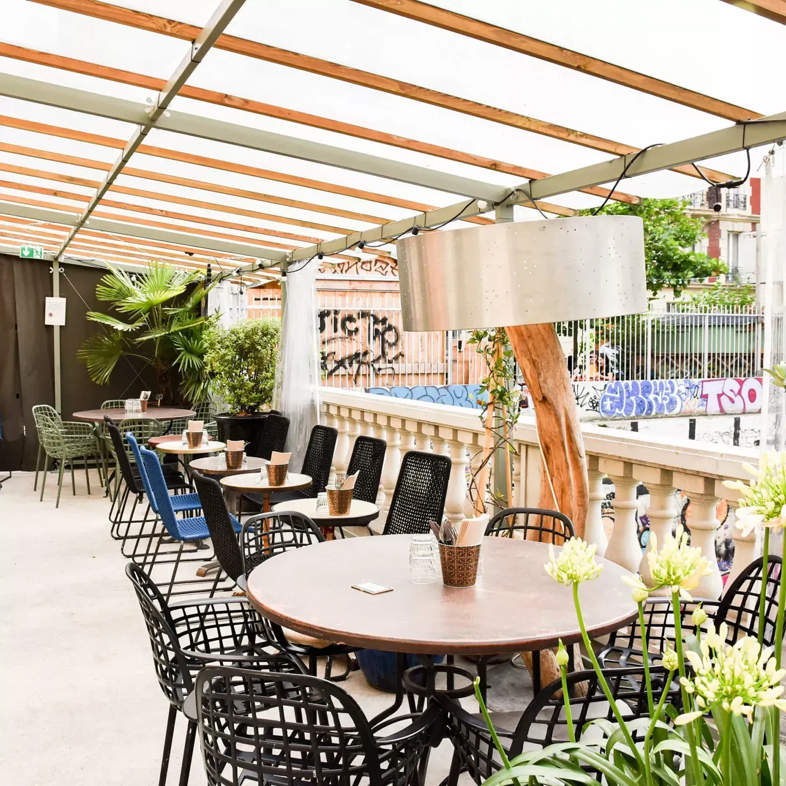 Covered terrace with round tables, black chairs and a pergola roof