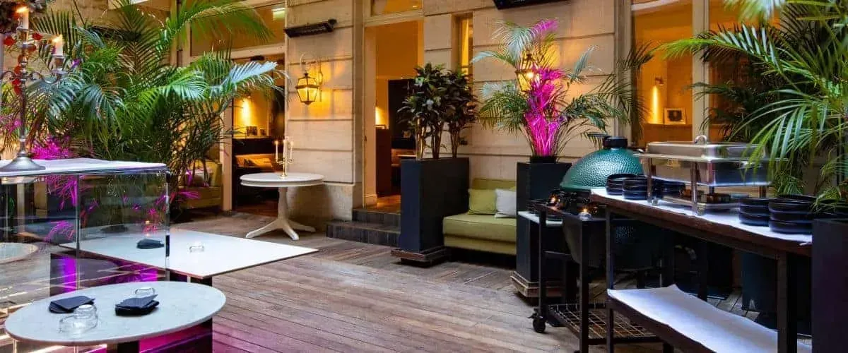 Terrace bar with plants, lanterns and pink flowers at night