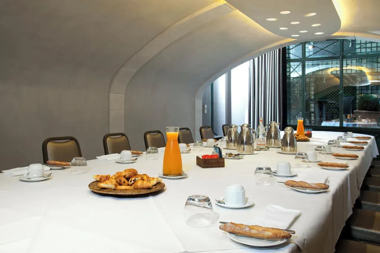 Long table with pastries and orange juice in the vaulted room